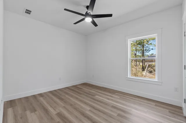 a view of empty room with wooden floor and fan