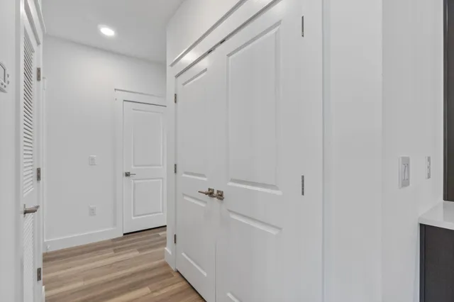an empty room with wooden floor a ceiling fan and windows