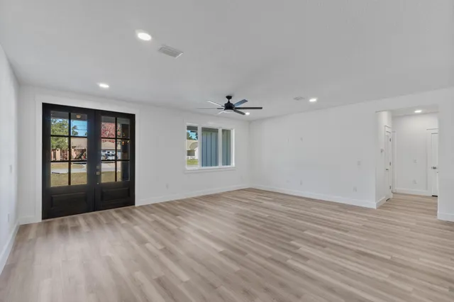 a view of an empty room with a window and wooden floor