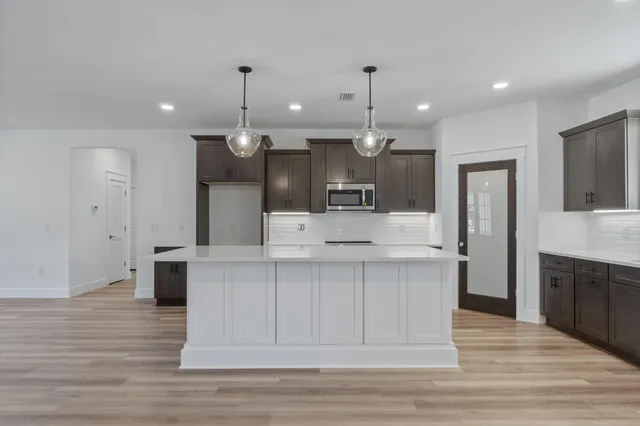 a large kitchen with a large counter top a sink stainless steel appliances and cabinets