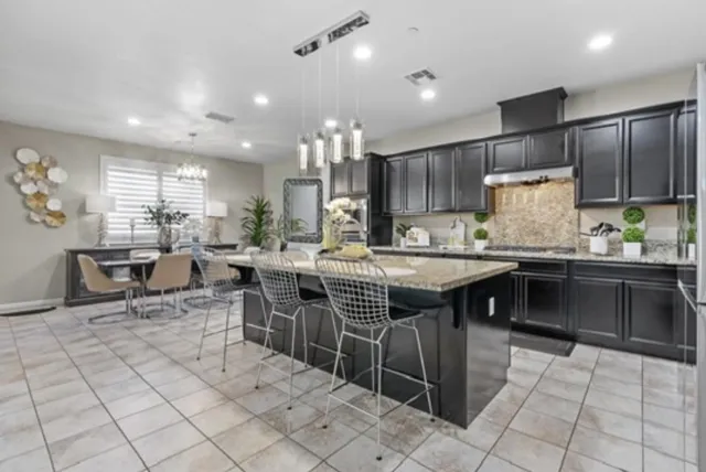 a kitchen with stainless steel appliances kitchen island granite countertop a table chairs and a refrigerator