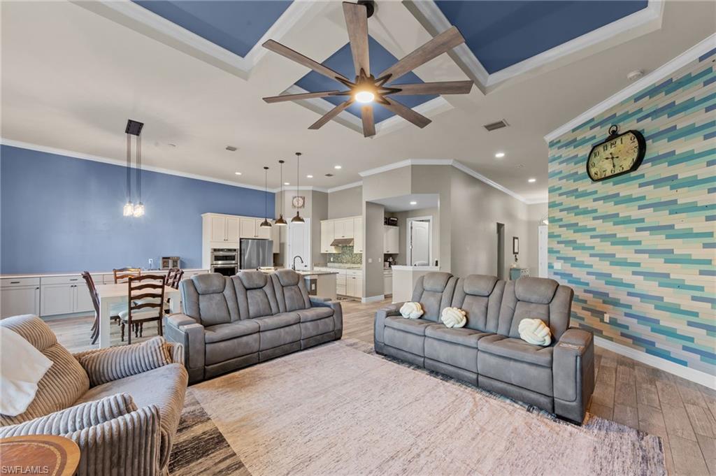 4914 Seton Way Immokalee, FL 34142 - Photo 16 of 46 Living area featuring an accent wall, wallpapered walls, wood finished floors, crown molding, and ceiling fan