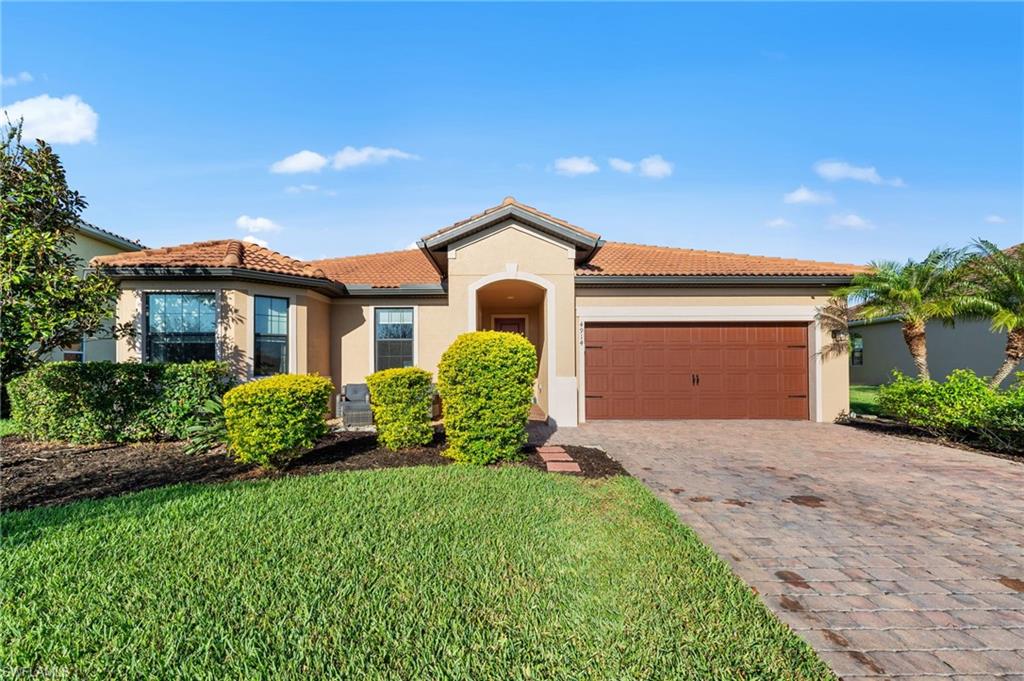 4914 Seton Way Immokalee, FL 34142 - Photo 2 of 46 Mediterranean / spanish-style house with a tile roof, an attached garage, stucco siding, decorative driveway, and a front yard
