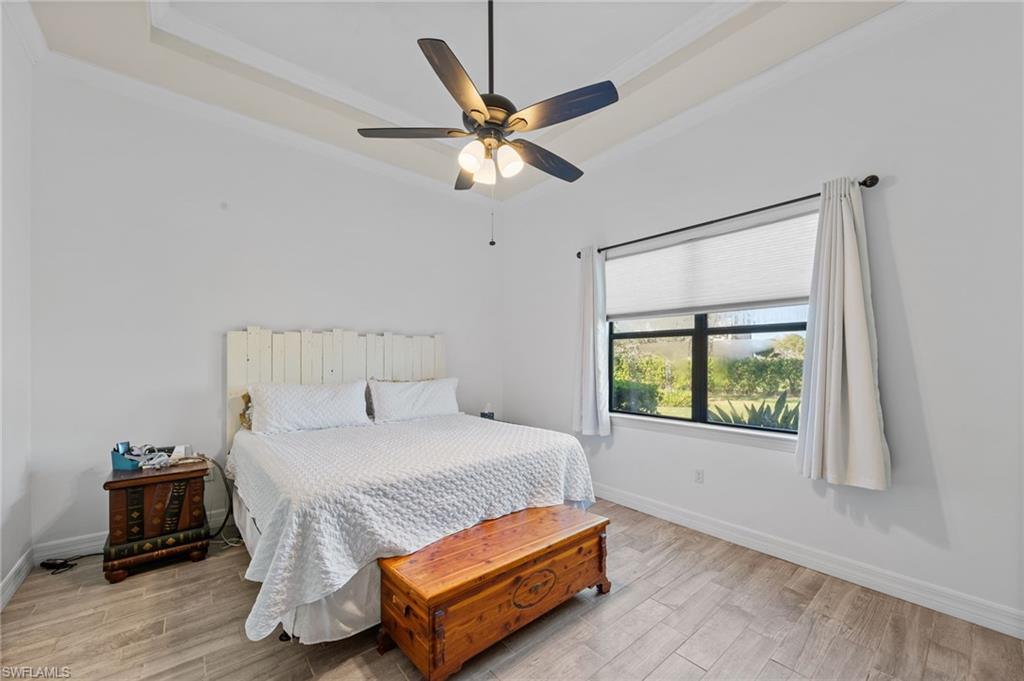 4914 Seton Way Immokalee, FL 34142 - Photo 26 of 46 Bedroom with light wood finished floors, crown molding, a ceiling fan, and a tray ceiling