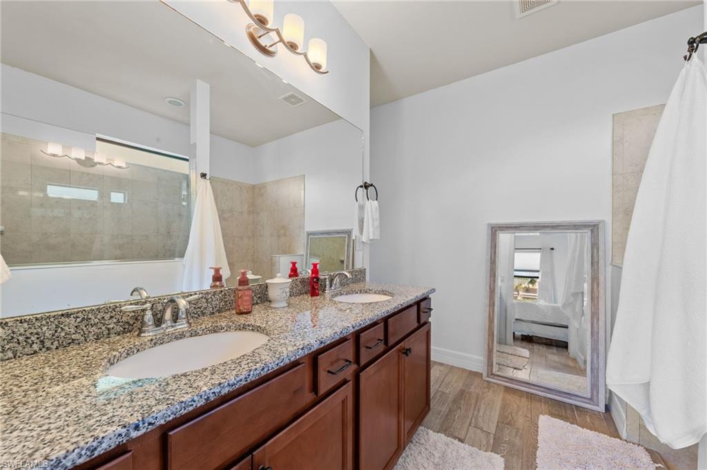 4914 Seton Way Immokalee, FL 34142 - Photo 28 of 46 Ensuite bathroom with double vanity, light wood-style flooring, and tiled shower