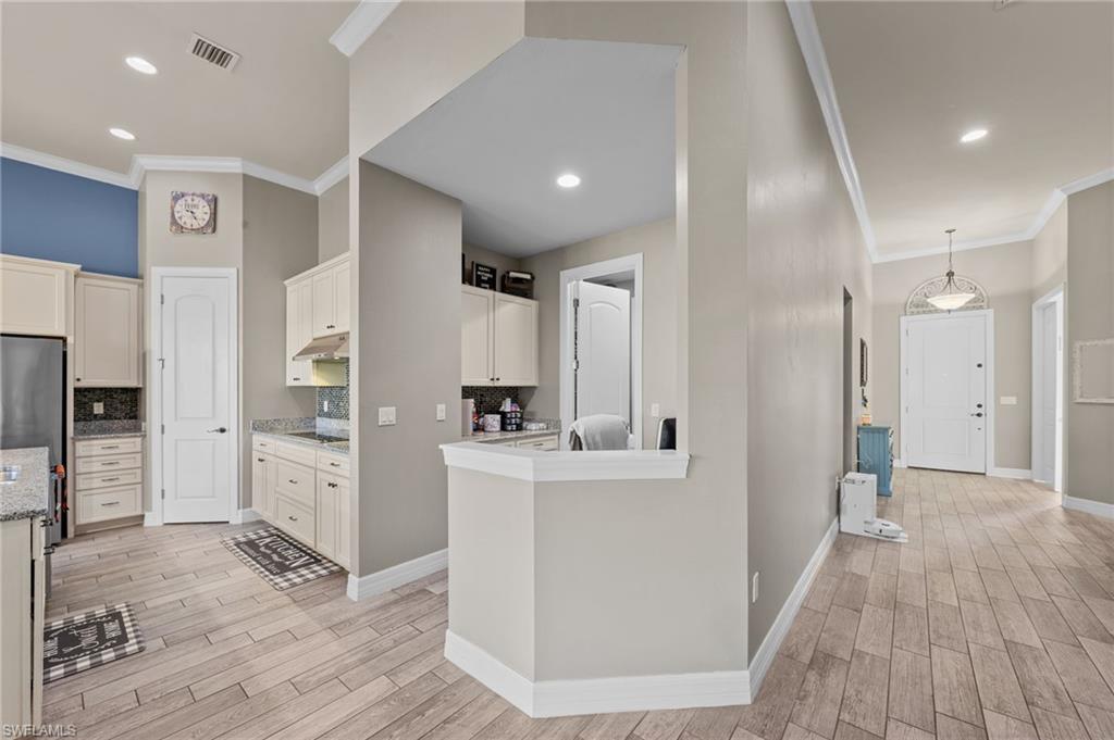 4914 Seton Way Immokalee, FL 34142 - Photo 6 of 46 Kitchen with ornamental molding, wood finish floors, backsplash, white cabinets, and recessed lighting