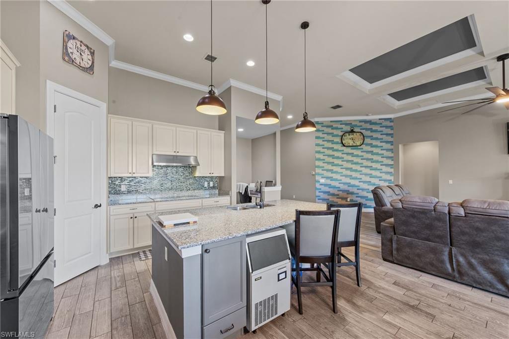 4914 Seton Way Immokalee, FL 34142 - Photo 10 of 46 Dual tone kitchen with high end refrigerator, light stone countertops, a center island with sink, open floor plan, and crown molding