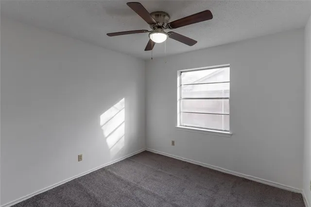 an empty room with window and ceiling fan