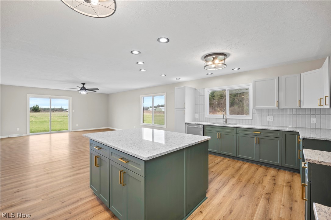 36220 Neff Road Grafton, OH 44044 - Photo 15 of 50 Two tone kitchen featuring backsplash, light stone counters, a kitchen island, light wood-style floors, and two tone cabinetry
