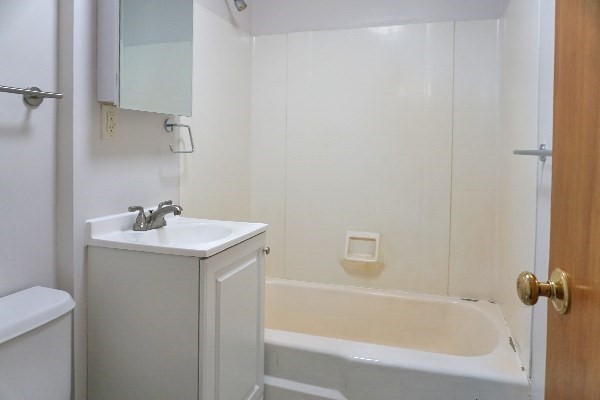 252 Ash Street, Unit 2 Waltham, MA 02453 - Photo 4 of 9 a bathroom with a granite countertop sink toilet and bathtub
