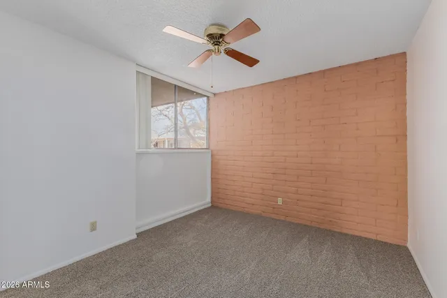 an empty room with a window and a fan