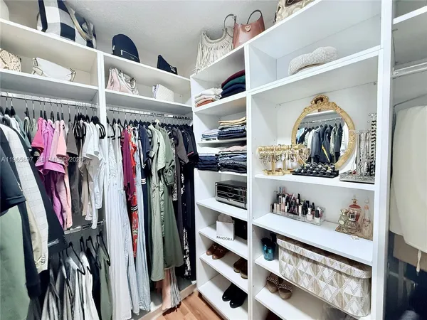 a view of walk in closet with clothes and shoes