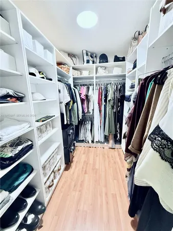a view of walk in closet with clothes and shoes