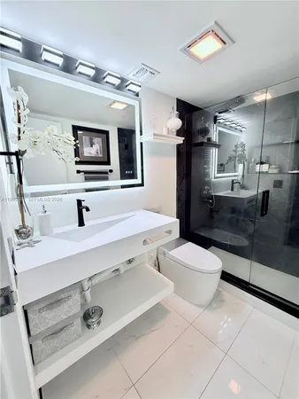 a bathroom with a sink a toilet a mirror and shower
