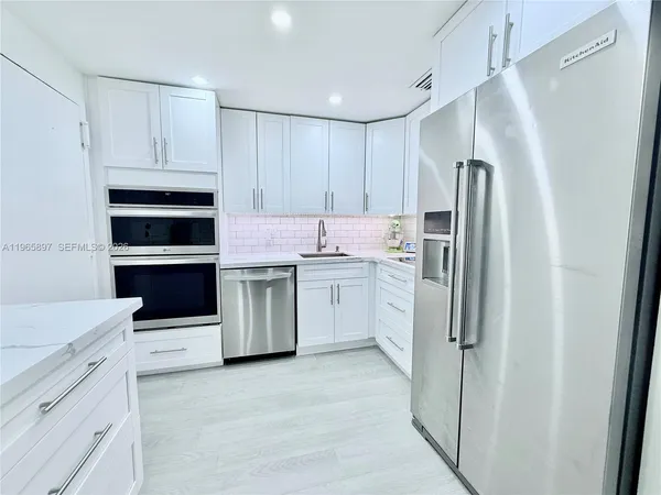 a kitchen with a refrigerator sink and cabinets