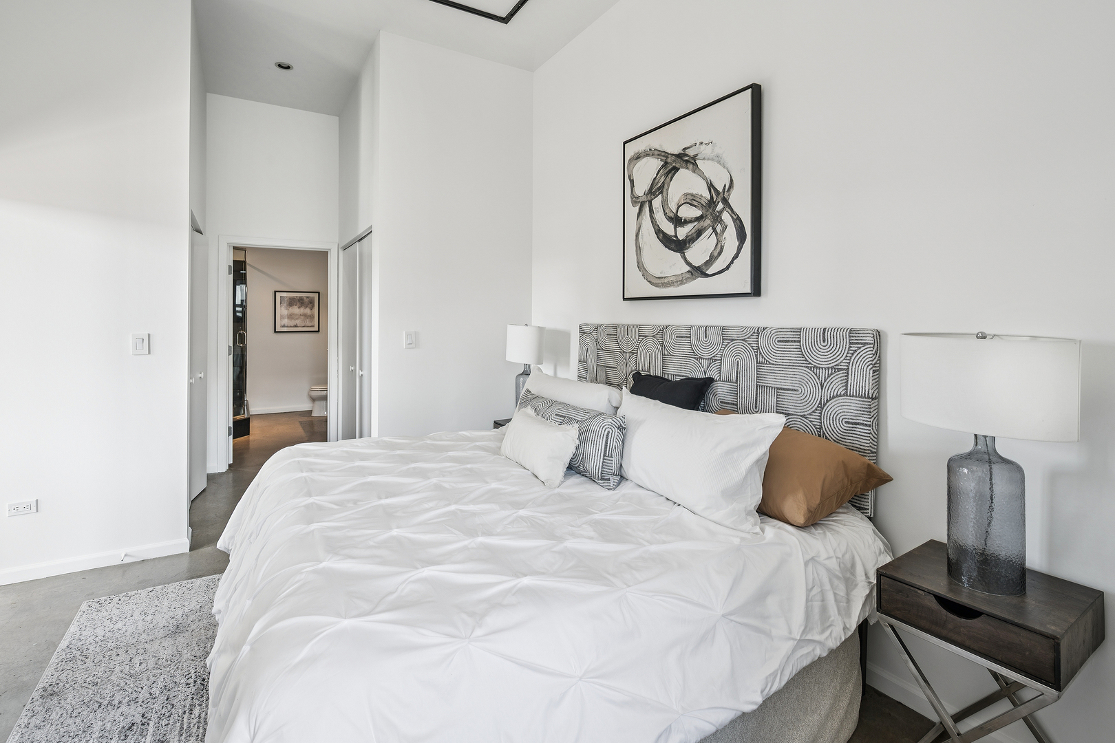 3631 North Halsted Street, Unit 308 Chicago, IL 60613 - Photo 13 of 20 a bedroom with a large bed and a lamp on dresser
