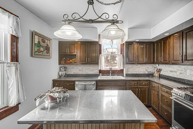 a large kitchen with stainless steel appliances a large center island attached withe living room