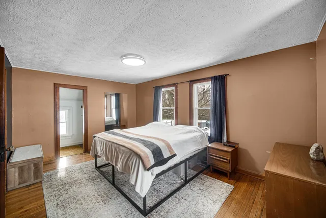 a spacious bedroom with a bed and wooden floor