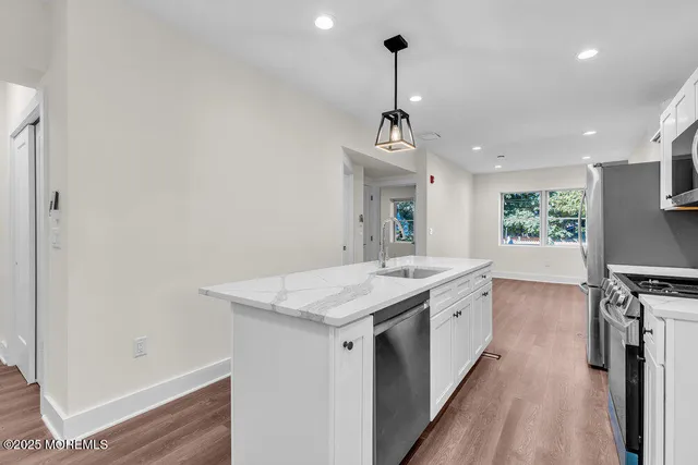 a kitchen with a sink stainless steel appliances and white cabinets