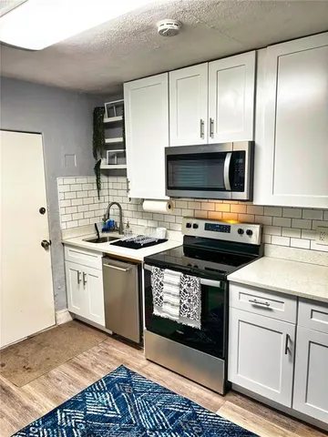 a kitchen with stainless steel appliances granite countertop a stove a sink and a microwave