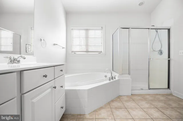 a spacious bathroom with a tub sink and mirror