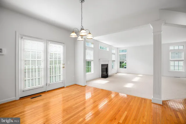 a view of an empty room with window and wooden floor