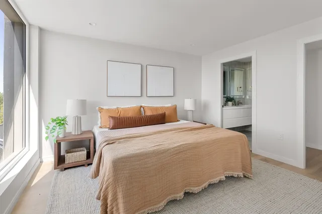 a bedroom with a bed lamp and a large window
