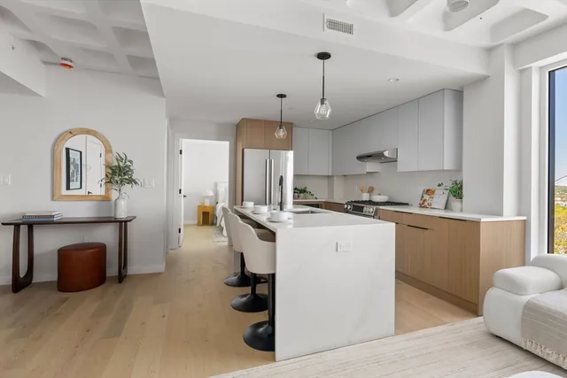 a kitchen with kitchen island a stove a refrigerator a oven a sink dishwasher and a fireplace with wooden floor