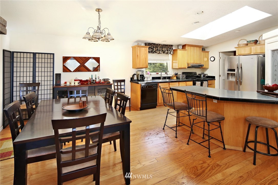 3125 Brown Road Ferndale, WA 98248 - Photo 5 of 24 a kitchen with stainless steel appliances granite countertop a stove top oven a sink a dining table and chairs with wooden floor