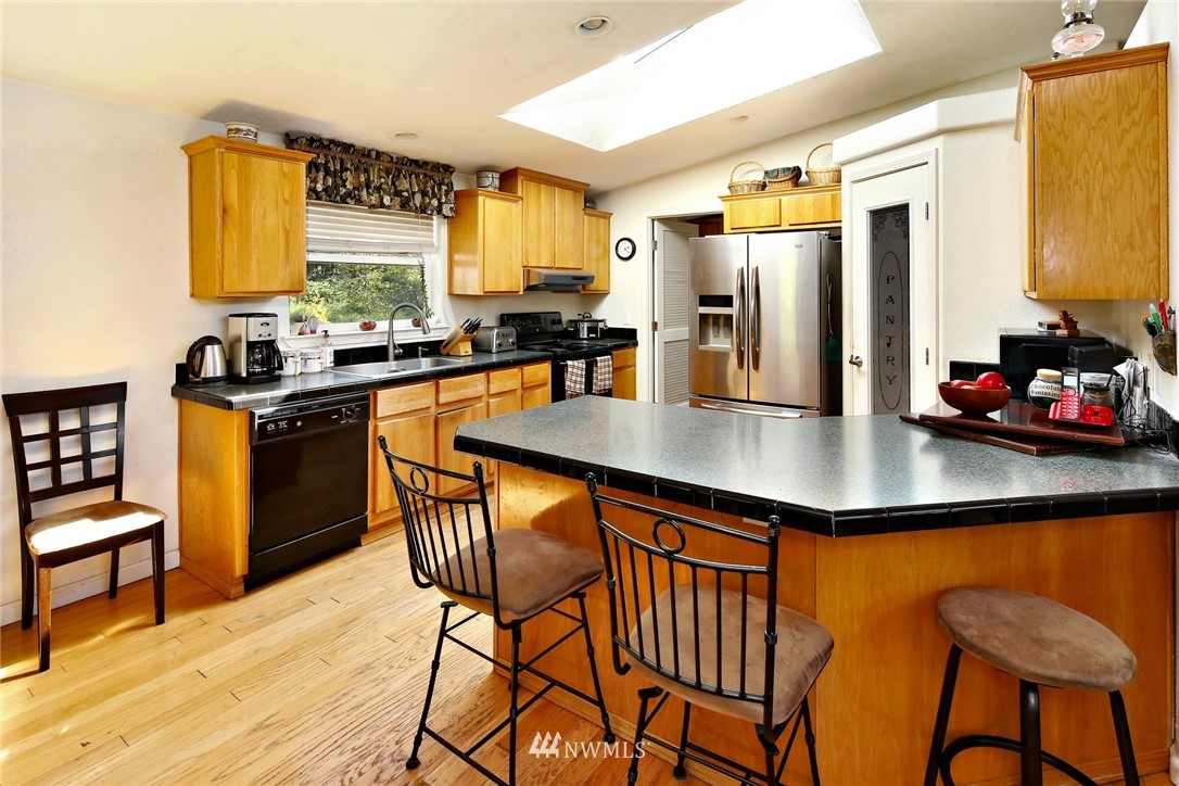 3125 Brown Road Ferndale, WA 98248 - Photo 6 of 24 a kitchen with stainless steel appliances granite countertop a stove top oven a dining table and chairs with wooden floor