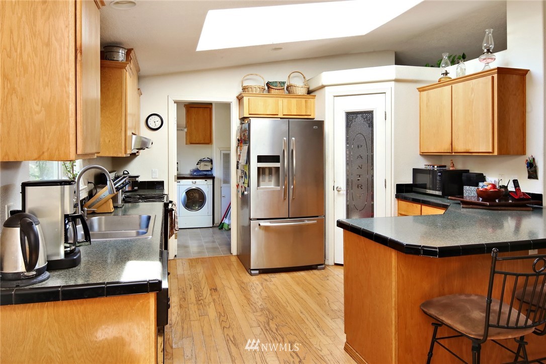 3125 Brown Road Ferndale, WA 98248 - Photo 8 of 24 a kitchen with stainless steel appliances granite countertop a refrigerator a sink dishwasher a stove and a dining table with wooden floor