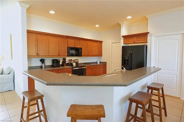 a kitchen with stainless steel appliances granite countertop a sink a stove a microwave a refrigerator and chairs