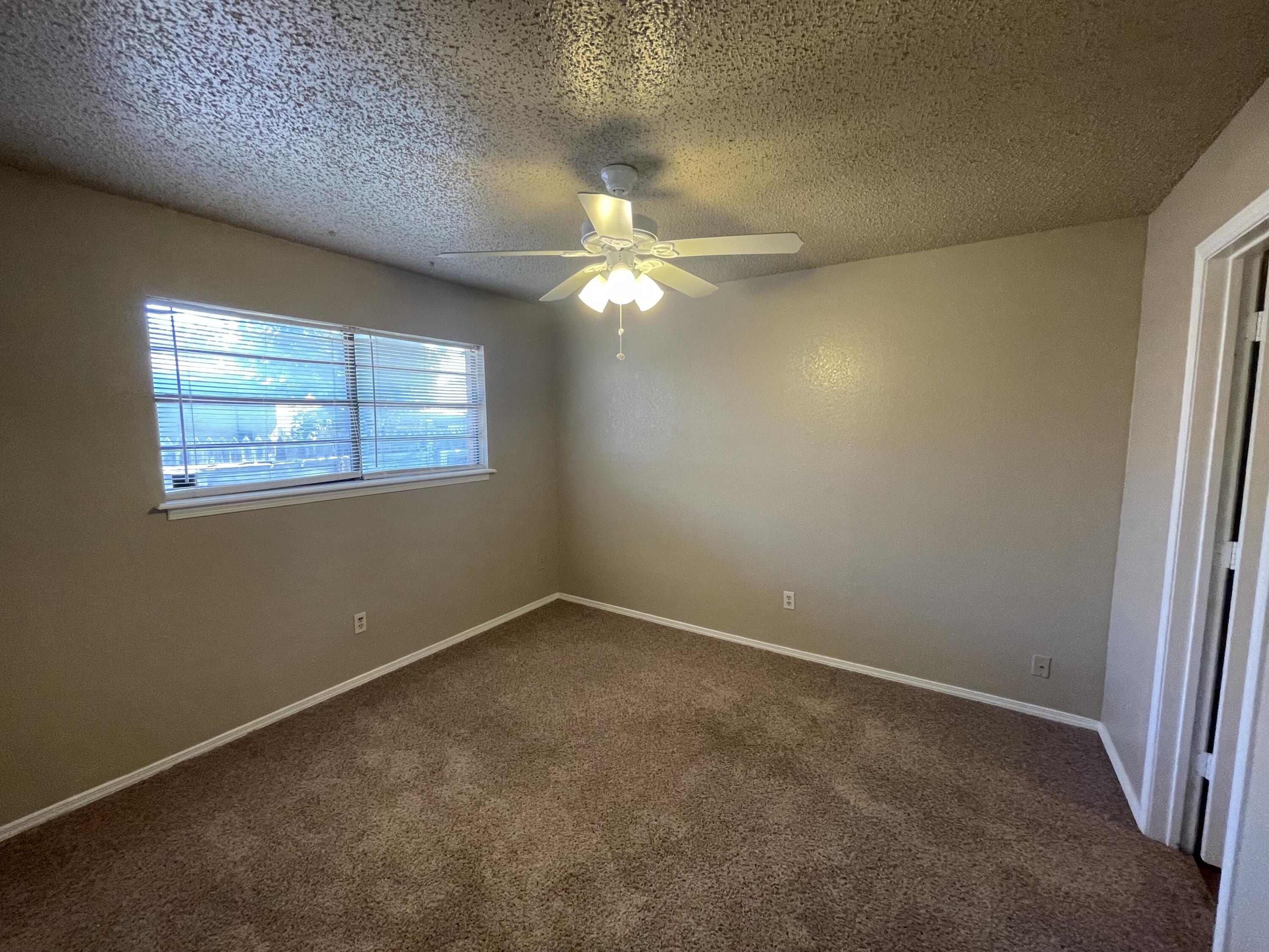 4413 75th Drive, Unit B Lubbock, TX 79424 - Photo 4 of 9 an empty room with windows and fan