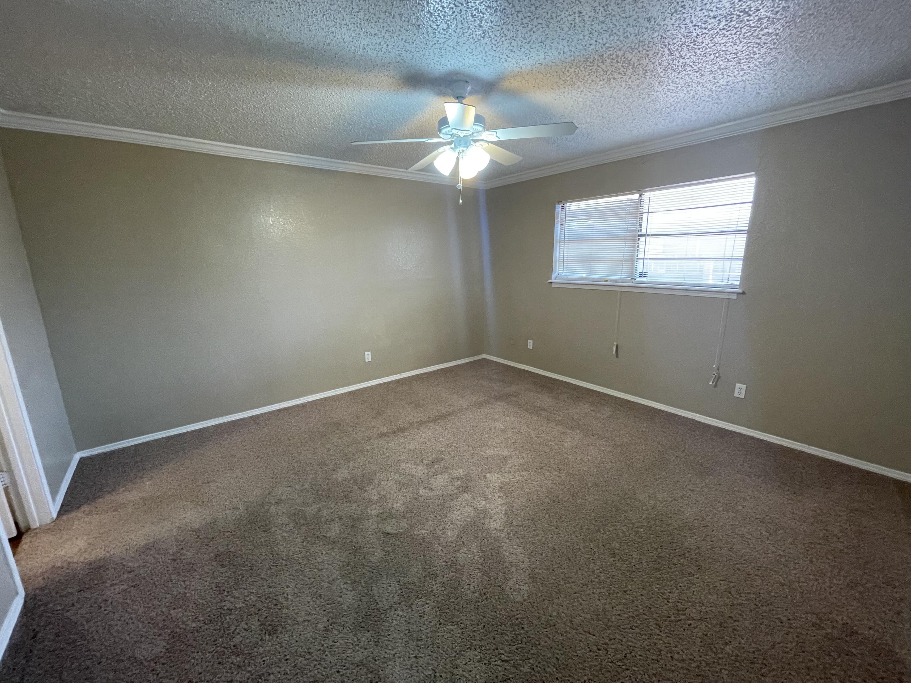4413 75th Drive, Unit B Lubbock, TX 79424 - Photo 7 of 9 an empty room with a chandelier fan and windows