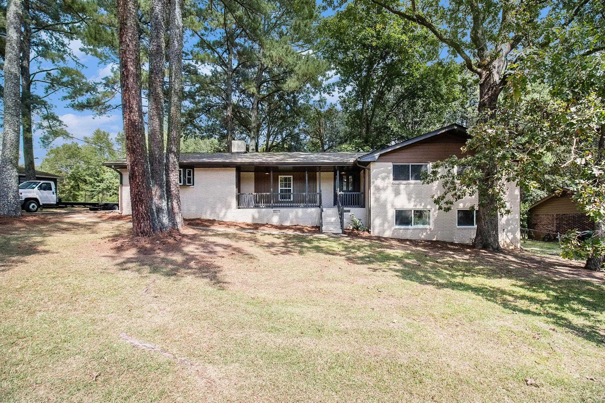 a view of a house with a yard and large tree