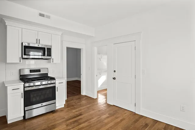 a kitchen with a refrigerator stove and wooden floor