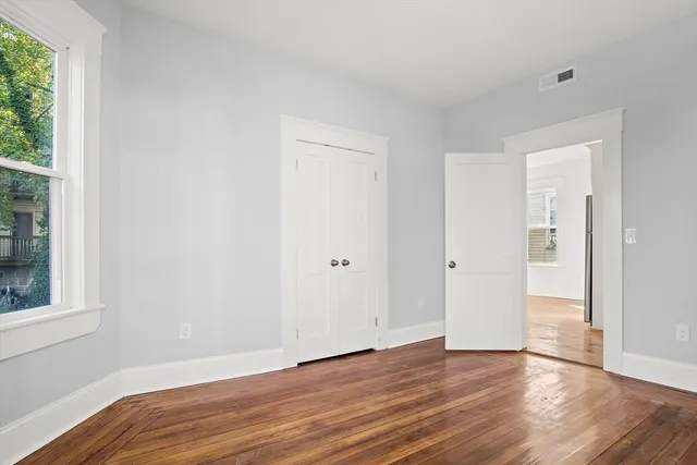 a view of an empty room with wooden floor and a window