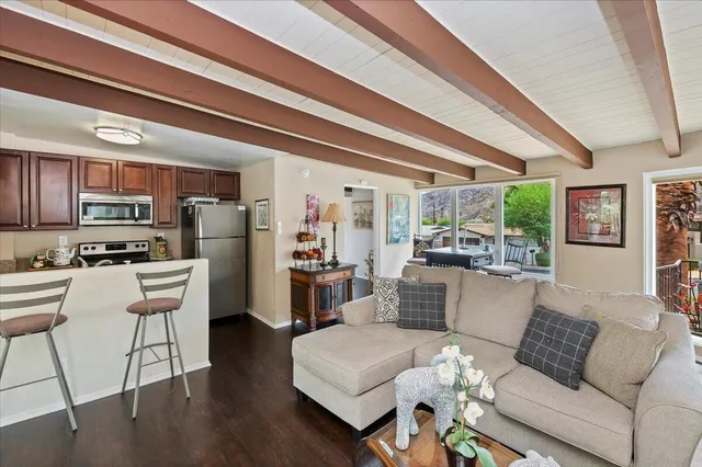 a living room with stainless steel appliances furniture and a kitchen view