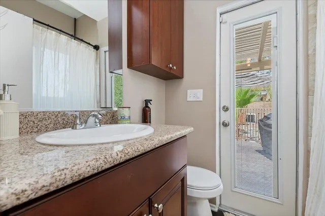 a bathroom with a granite countertop sink a toilet and a shower