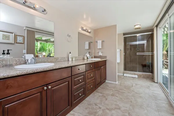 a spacious bathroom with a double vanity sink a mirror and a shower