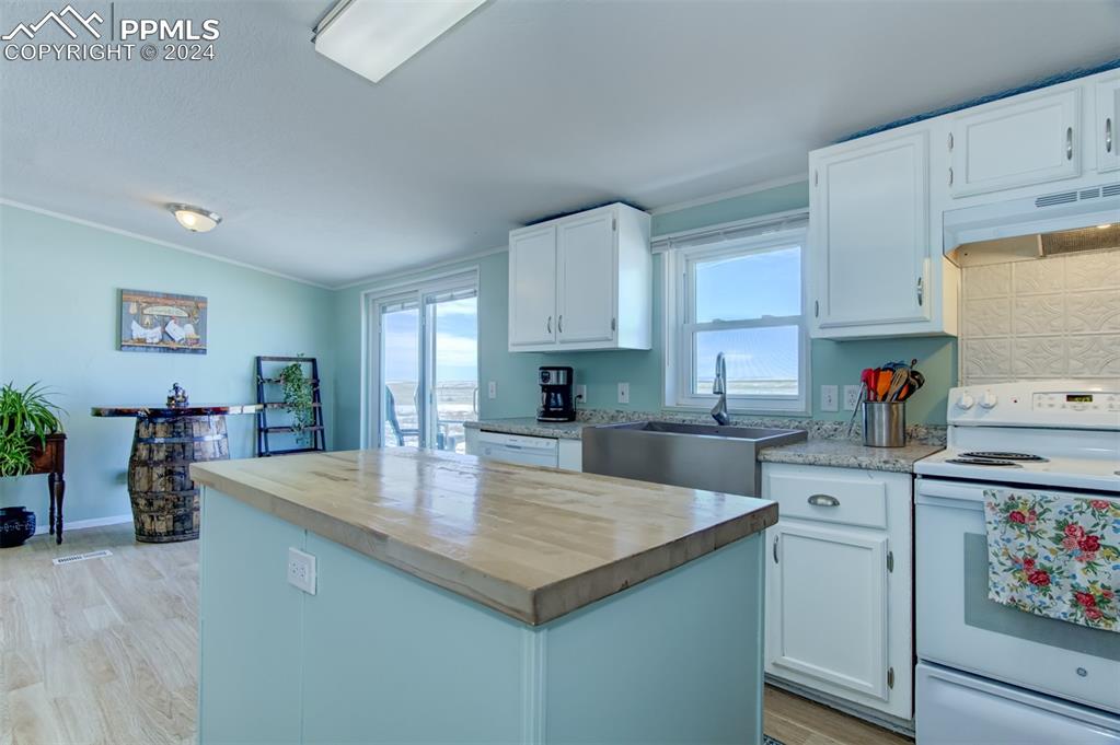 7270 South Yoder Road Yoder, CO 80864 - Photo 9 of 37 a kitchen with a stove top oven a sink dishwasher and white cabinets with wooden floor
