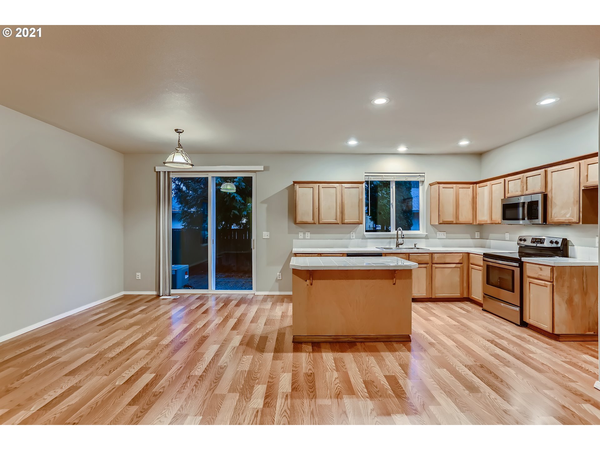 17670 Southwest September Lane Beaverton, OR 97003 - Photo 15 of 31 a open kitchen with granite countertop a refrigerator oven a sink dishwasher and white cabinets with wooden floor