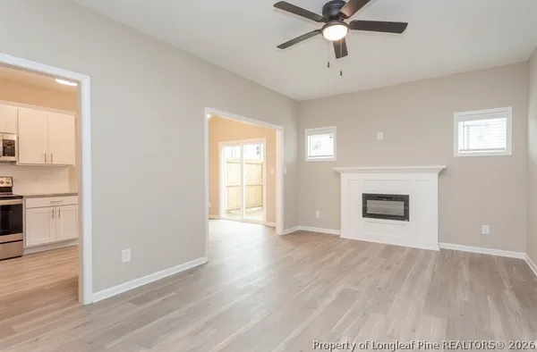 an empty room with wooden floor ceiling fan and windows