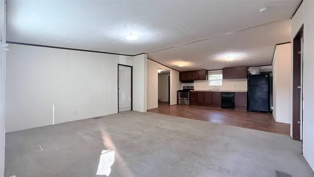 an empty room with a kitchen and a refrigerator