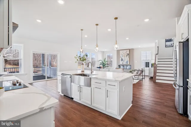 a large kitchen with kitchen island lots of counter space a sink appliances and a living room view