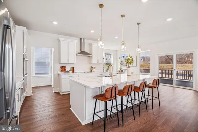a kitchen with stainless steel appliances a dining table chairs refrigerator sink and microwave