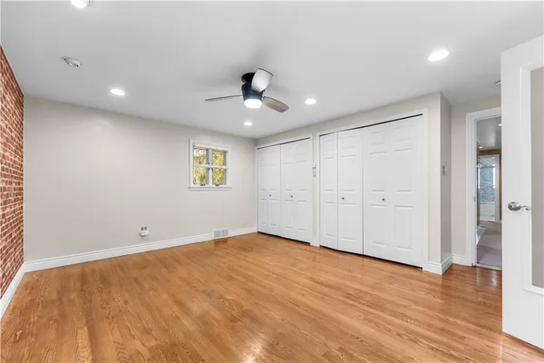 a view of an empty room with wooden floor and a ceiling fan