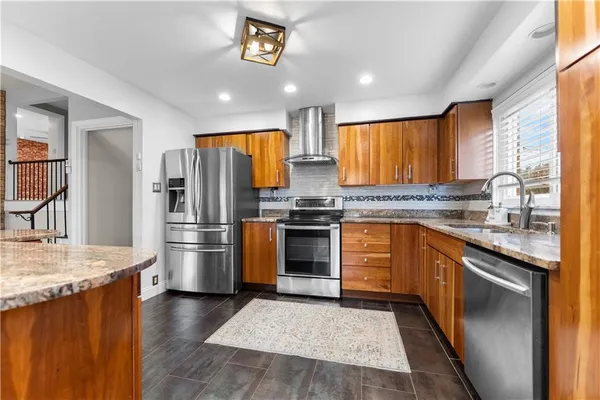 a kitchen with stainless steel appliances granite countertop a refrigerator a stove a sink and a microwave