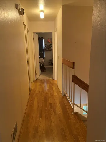 a view of a hallway with wooden floor and a bathroom