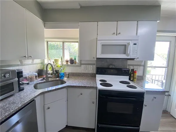 a kitchen with granite countertop white cabinets sink and window